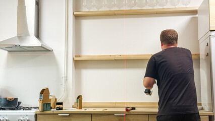 Crafting a shelf with methodical precision, a Caucasian man embodies DIY spirit, embodying origins...
