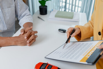 A car sales negotiation takes place in an office where a female salesperson in a yellow blazer explains details of a contract to a male client, showing car models and handing over keys.