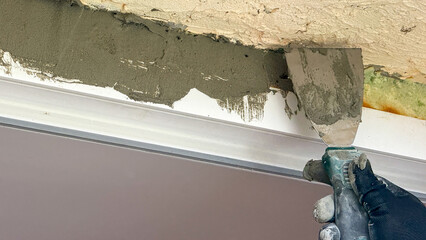 A skilled artisan's gloved hand dances with plaster on aged walls, evoking ancient craft rituals...