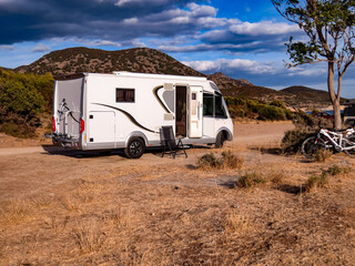 Camper van by the sea, a white camper van parked near the seaside under a clear blue sky. Concept of travel, vacation, freedom, and outdoor camping lifestyle.