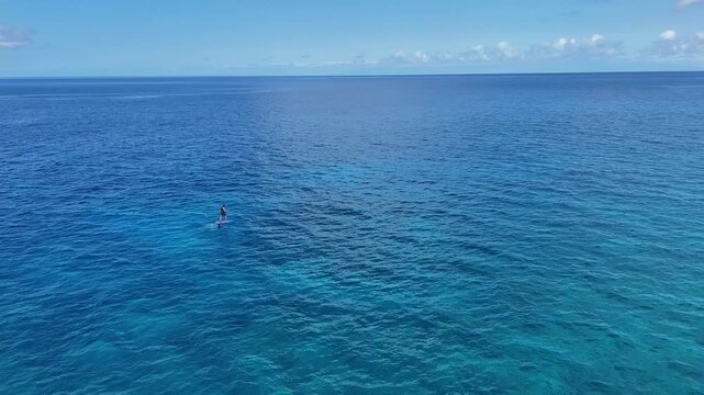 Aerial view of a person on a hydrofoil board gliding across the turquoise and deep blue ocean waters, a serene and vibrant scene, Hawi, Hawaii, United States.