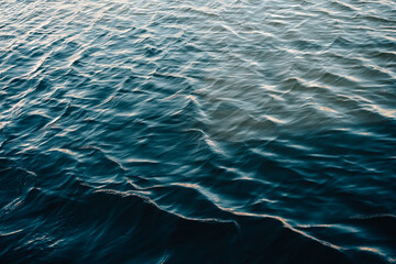 Serene deep blue ocean waves shimmer with golden sunlight, creating a tranquil and dynamic natural texture perfect for relaxation themes.