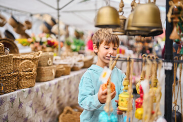 Boy smiling while choosing handmade crafts at flea market