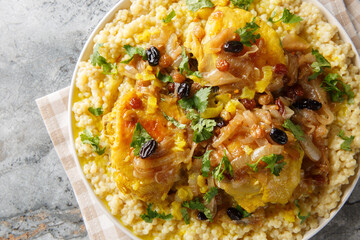Chicken Couscous Tfaya With Caramelized Onion and Raisin closeup on the plate on the table. Horizontal top view from above