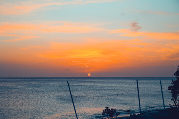 Floating in the waves at sunset, sun just above horizon, going down, orange sky, tranquil sea. Peaceful moment, vacations, summer mood. Dominican Republic. Horizontal video.