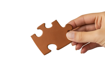 Hand holding a single brown puzzle piece isolated on transparent background. Hand holding single piece of puzzle isolated on white background.
