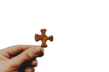 Hand holding a single brown puzzle piece isolated on transparent background. Hand holding single piece of puzzle isolated on white background.