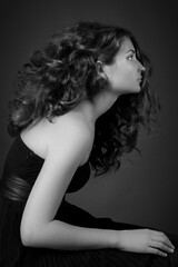 A black and white profile portrait of a woman with voluminous curly hair. Elegant fashion and beauty model posing in a studio. Classic hairstyle concept. © Yana Zastolskaya