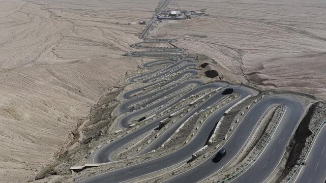 Aerial view of the winding Panlong Ancient Road slicing through the arid landscape, a ribbon of grey against a canvas of beige, Panlong Ancient Road, China.