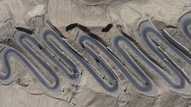 Aerial view of the winding Panlong Ancient Road cutting through the rugged terrain, a ribbon of asphalt against the barren landscape, Panlong Ancient Road, China.
