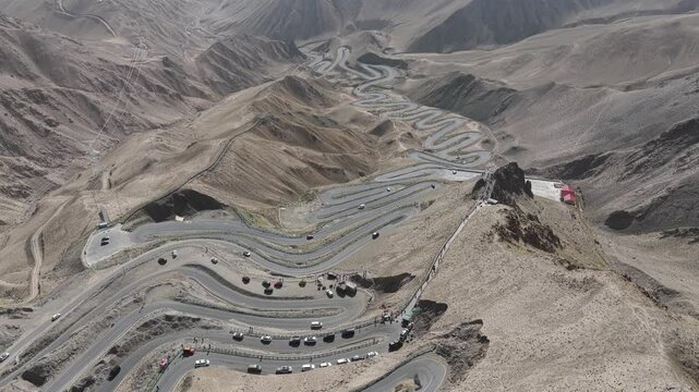 Aerial view of the winding Panlong Ancient Road snaking through the arid landscape, showcasing a stark contrast of grey roads and brown mountains, Panlong, China.
