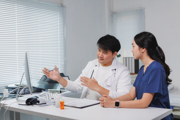 Doctors discussing patient's medical records on computer in hospital room