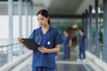 Focused doctor reading medical chart in hospital corridor