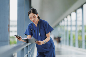Doctor using smartphone and reading medical record in hospital corridor
