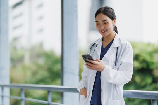 Smiling doctor using smartphone in hospital corridor
