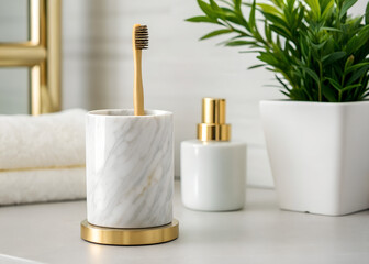 Bamboo toothbrush rests in marble holder with gold accents. Potted green plant and diffuser stand nearby. Clean bathroom countertop decor highlights hygiene and eco-friendly design.