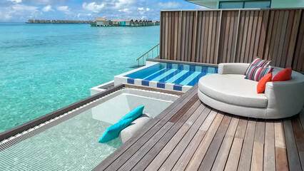A private overwater deck featuring a circular sofa, plunge pool and hanging net over the crystal clear ocean at a Maldives resort