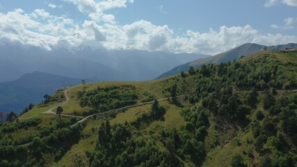 Paragliding in the mountains against the backdrop of a beautiful mountain landscape on a summer day.