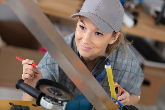 female carpenter using electric sander for wood