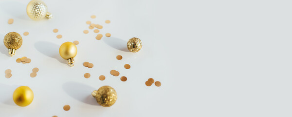 Golden Christmas balls and confetti on a white table in bright light