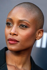 Obraz premium A close-up portrait of a stylish Black woman with a shaved head, bright lipstick, and a thoughtful look to the side