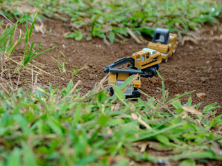 Yellow Construction Vehicles on Soil with Green Grass, Outdoor Toy Scene