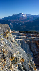 An open pit mining quarry set within a mountainous landscape symbolizing industrial power resource extraction and human impact representing scale effort and the transformation of natural terrain