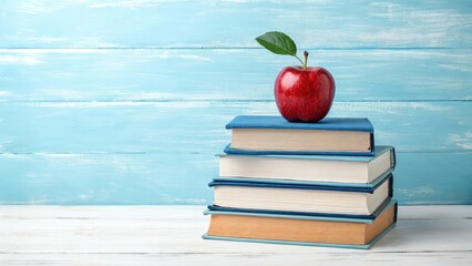 A red apple with a leaf resting on a stack of blue books