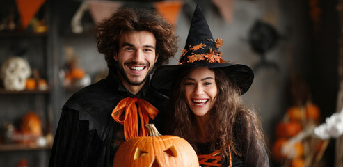Young happy couple in witch costume holding carved pumpkin celebrating Halloween party