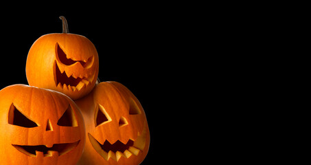 Halloween poster design. Pumpkins with carved spooky faces peeking out against black background. Space for text
