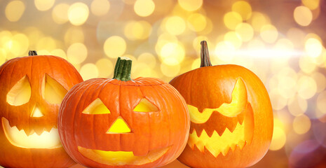 Halloween jack-o-lanterns. Pumpkins with carved creepy faces, bokeh effect
