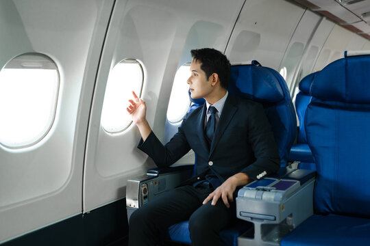 Young Asian executive excels in first class, multitasking with digital tablet, laptop and smartphone. Travel in style, work with grace.