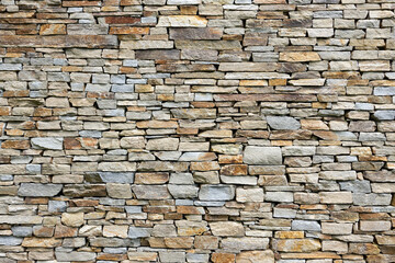 Fototapeta premium Textured stone wall composed of various sizes and colors of natural stones, showcasing a rustic and earthy aesthetic, ideal for architectural and design backgrounds