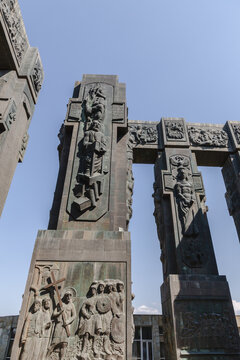 View of imposing stone pillars adorned with intricate carvings reach towards the clear sky, a testament to history and artistry, Chronicle of Georgia, Tbilisi, Georgia.