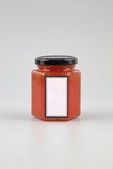 A jar of jam with a blank label on a light background.