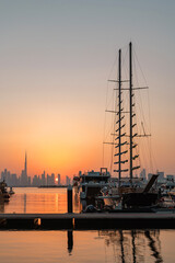 Dubai Creek Harbour Marina sunset with yachts, Burj Khalifa and Downtown skyline glowing in evening light