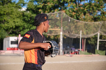 Young baseball player holding a baseball glove and ball in hand, ready for action