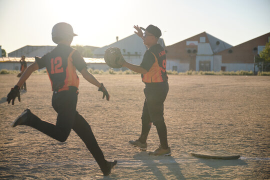 Players celebrating on baseball field, showing sportsmanship and teamwork at sunset - Powered by Adobe
