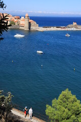 Two people looking out across bay in Collioure, France featuring Notre-Dame-des-Anges church and Saint-Vincent chapel 