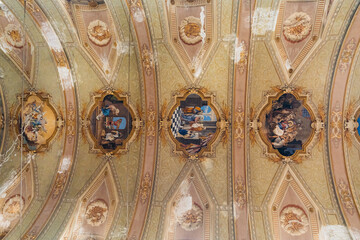 View of frescoes and ornate detailing on the vaulted ceiling, with muted pinks and greens contrasting the peeling paint, creating a textured decay, Bergamo, Lombardy, Italy.