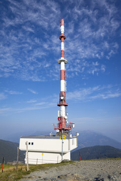 View of a tall, red and white communication tower rises against a clear blue sky dotted with fluffy clouds, Goldeck, K&Atilde;&curren;rnten, Austria.