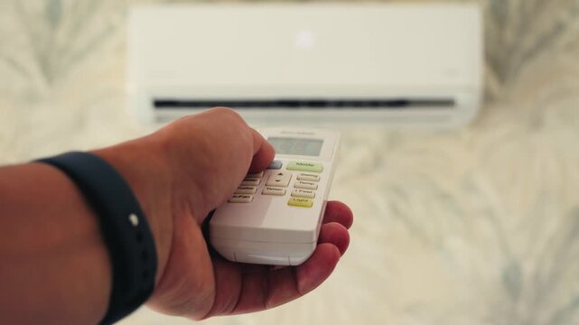 Close up of a hand holding an air conditioner remote pointing. Hand using remote controller for adjust Air conditioner.