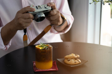 The film camera is photographing drinks on the table, illustrating the hobby of food photography and urban lifestyle.