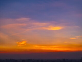 Fototapeta premium Breathtaking Twilight Sky with Vibrant Orange and Purple Clouds Over Silhouetted Landscape Horizon