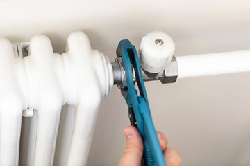 Plumber man is blocking repairs radiators of heating battery in apartment tap.