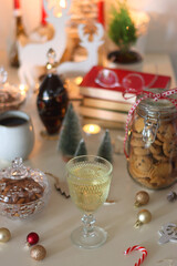 Cookie jar, tea, wine, nuts, books, lit candles and Christmas decorations on the table. Cozy Christmas hygge at home. Selective focus.
