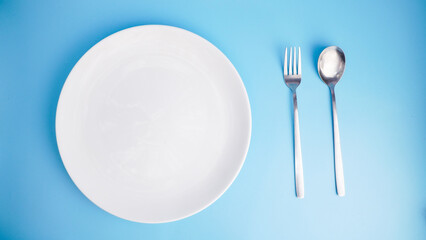 Empty Plate with Fork and Spoon on Blue Background
