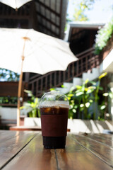 Iced Americano coffee served at garden table. Summer garden scene