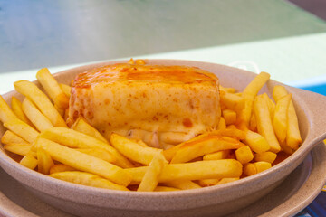 Francesinha sandwich with french fries on a plate. Typical food from Porto, Portugal