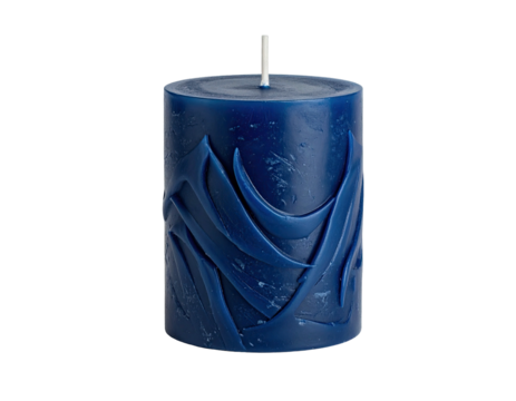 A blue cylindrical candle with carved abstract designs and a white wick, black background